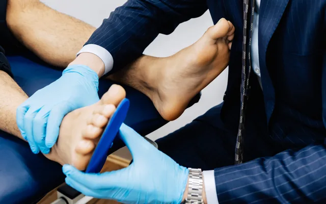 A podiatrist holding a custom orthotic against a patient’s foot