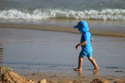A young child walking on the sand