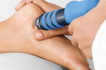 A shockwave applicator held against the back of the heel