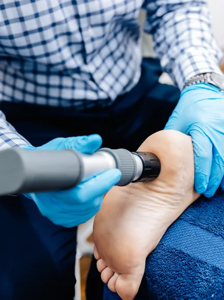 A shockwave therapy handpiece being applied to a patient’s heel
