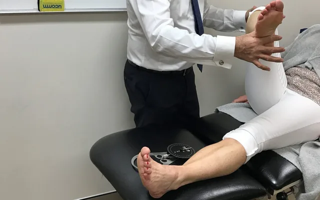 A Dr. Abbie Clinics podiatrist examining a patient’s lower leg and foot