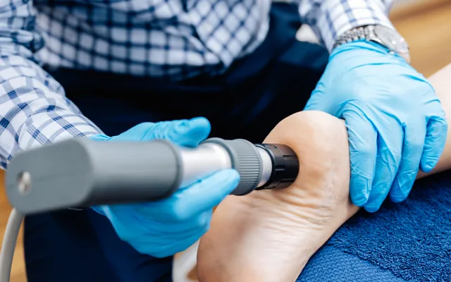 A shockwave therapy handpiece being applied to a patient’s heel